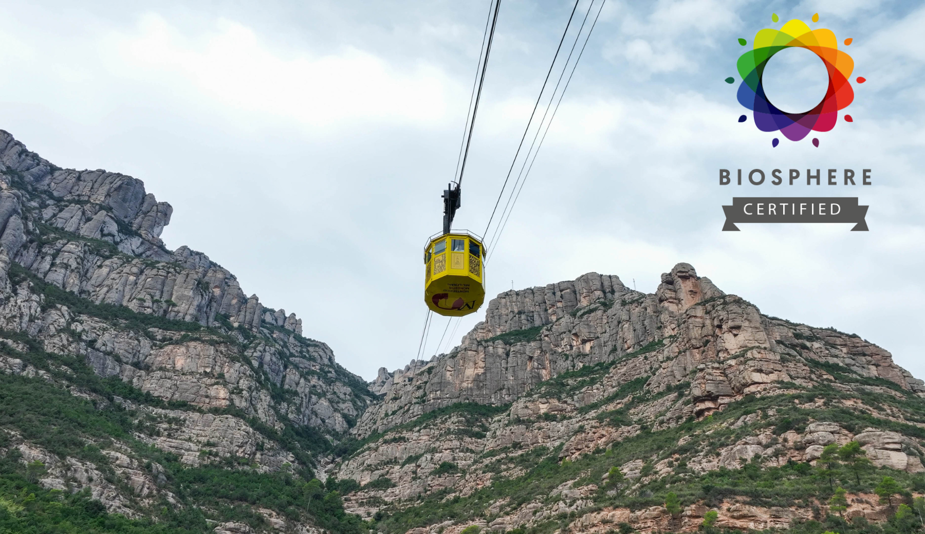 L’Aeri de Montserrat en funcionament amb les muntanyes de Montserrat de fons i el segell Biosphere Certified, que acredita el seu compromís amb la sostenibilitat i el turisme responsable